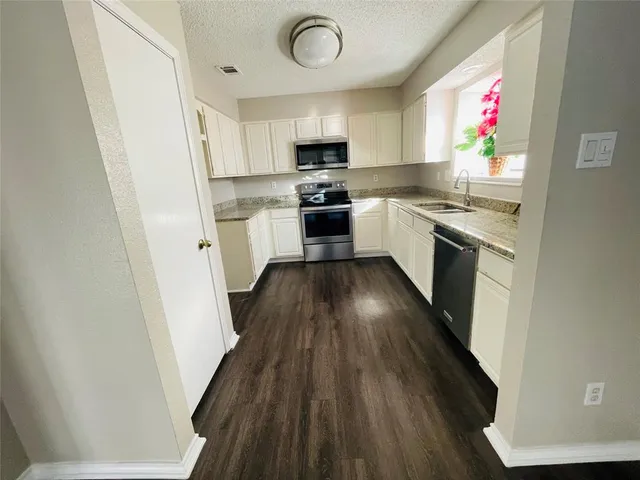 a kitchen with granite countertop a stove top oven a sink dishwasher and a microwave oven with wooden floor