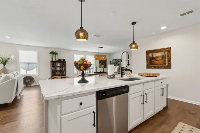 a kitchen with stainless steel appliances kitchen island granite countertop a sink a stove a dining table and chairs with wooden floor