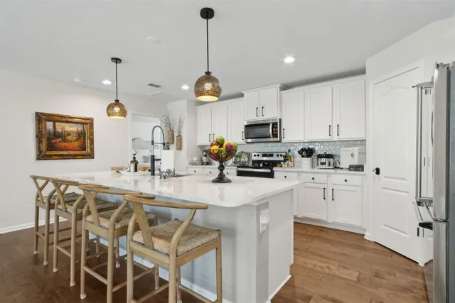 a kitchen with kitchen island white cabinets and stainless steel appliances