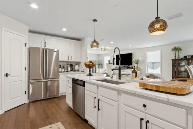 a kitchen with stainless steel appliances granite countertop a refrigerator sink and white cabinets