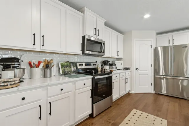 a kitchen with white cabinets and appliances