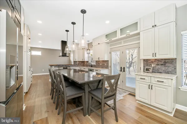 a kitchen with kitchen island a stove a refrigerator and a dining table with wooden floor