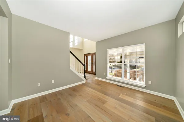 a kitchen with stainless steel appliances kitchen island granite countertop a refrigerator a stove a sink and white cabinets with wooden floor