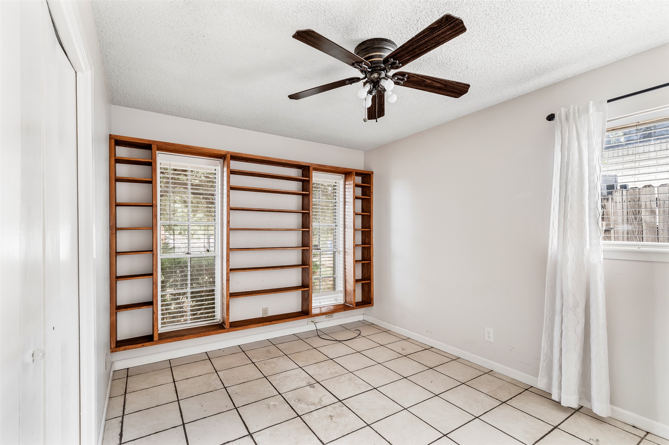 7506 Glenhill Road Austin, TX 78752 - Photo 12 of 24 Integrated shelving units frame the sunlit windows of this room.