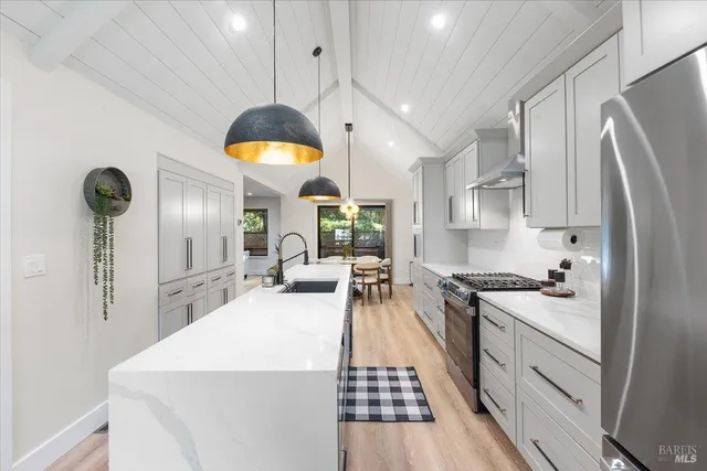 a kitchen with stainless steel appliances a stove a sink a refrigerator cabinets and living room view