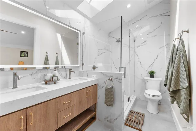 a bathroom with a sink a toilet a large mirror and shower