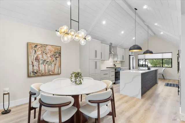 a dining room with chandelier and wooden floor