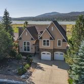 a front view of a house with a yard and mountain view in back