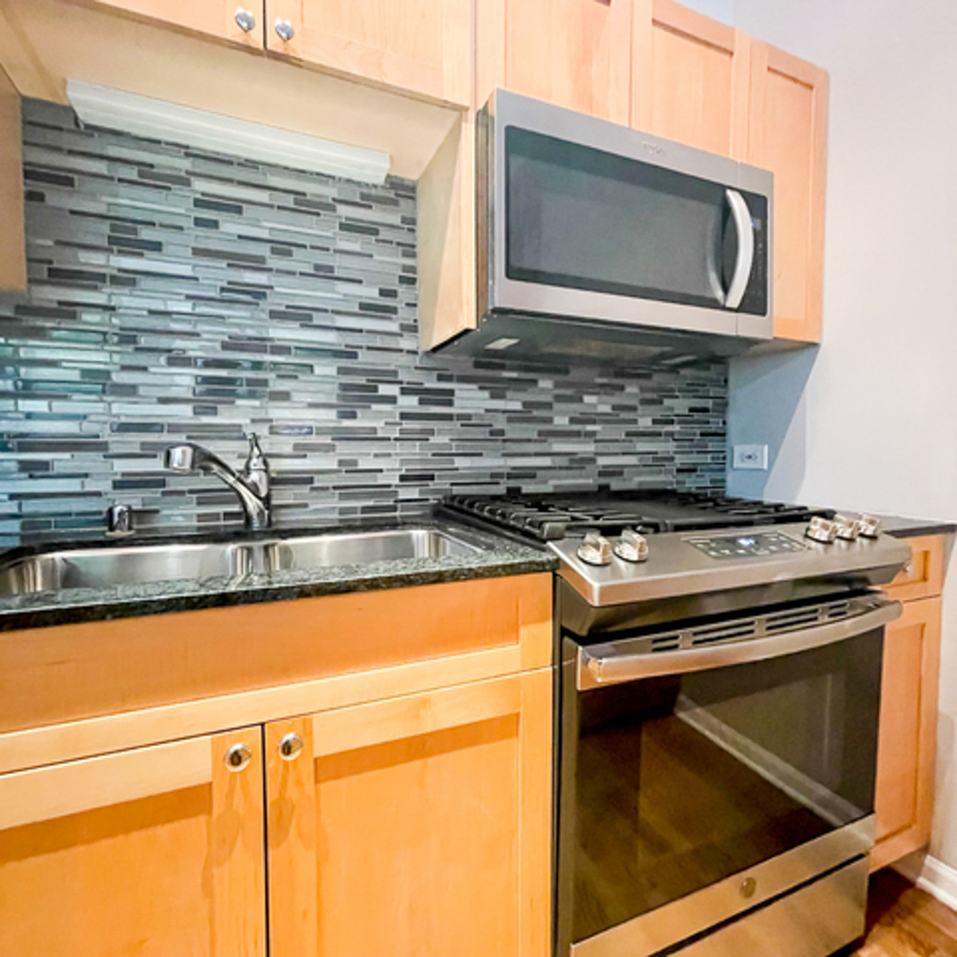 520 West Huron Street, Unit 116 Chicago, IL 60654 - Photo 10 of 28 a kitchen with granite countertop cabinets stove top oven and microwave