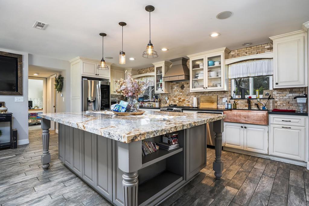 2430 Geyer Lane Alpine, CA 91901 - Photo 11 of 60 a kitchen with stainless steel appliances granite countertop a kitchen island a stove a sink a oven and a dining table with wooden floor