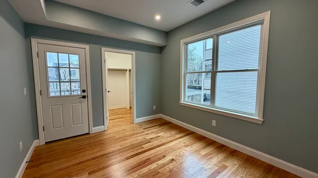an empty room with wooden floor and windows