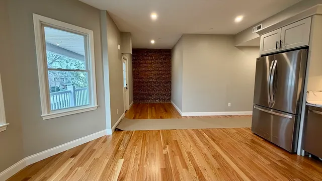 a view of empty room with wooden floor and window