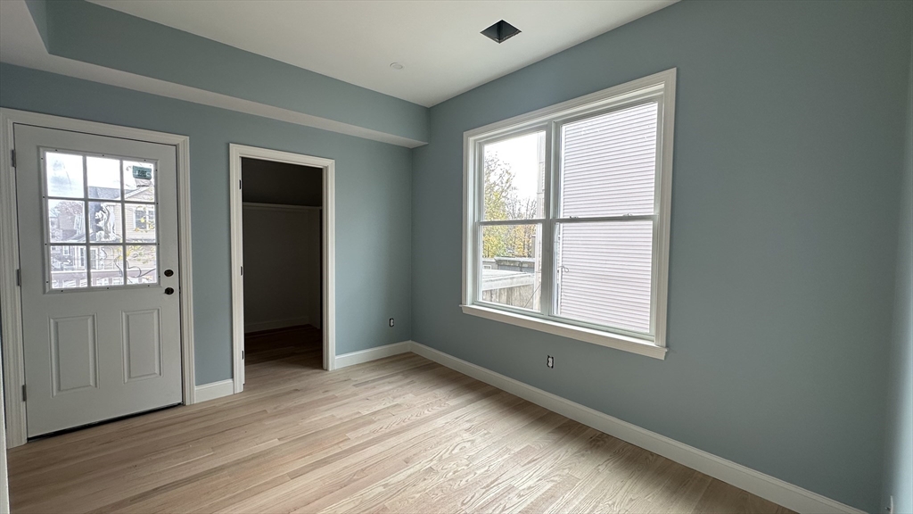663 Columbia Road, Unit 2 Boston, MA 02125 - Photo 10 of 17 an empty room with wooden floor and windows