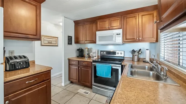 a kitchen with stainless steel appliances granite countertop a stove a sink and a microwave