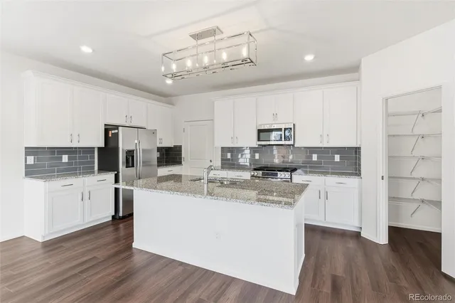 a large kitchen with stainless steel appliances a large counter top a stove and a refrigerator