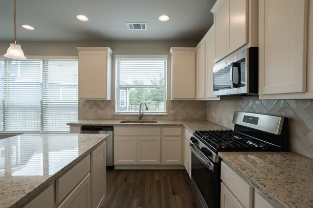 a kitchen with stainless steel appliances granite countertop a stove a sink and a microwave
