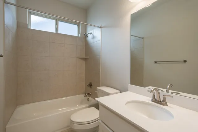 a bathroom with a bathtub shower sink vanity mirror and toilet