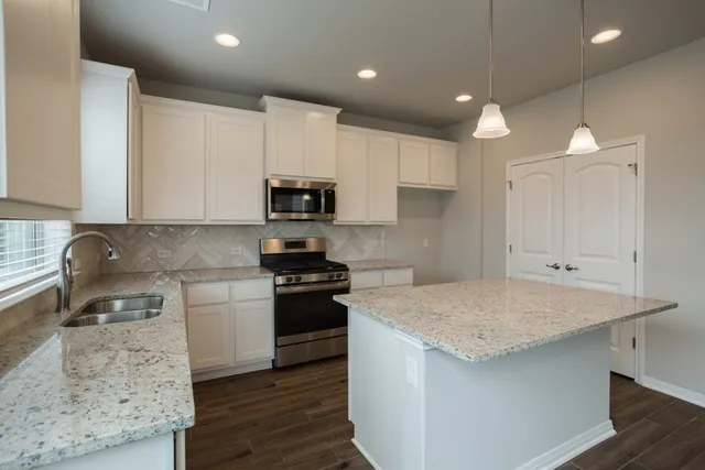 a kitchen with granite countertop a sink stove and refrigerator