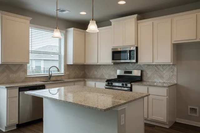 a kitchen with stainless steel appliances granite countertop a sink a stove and a microwave