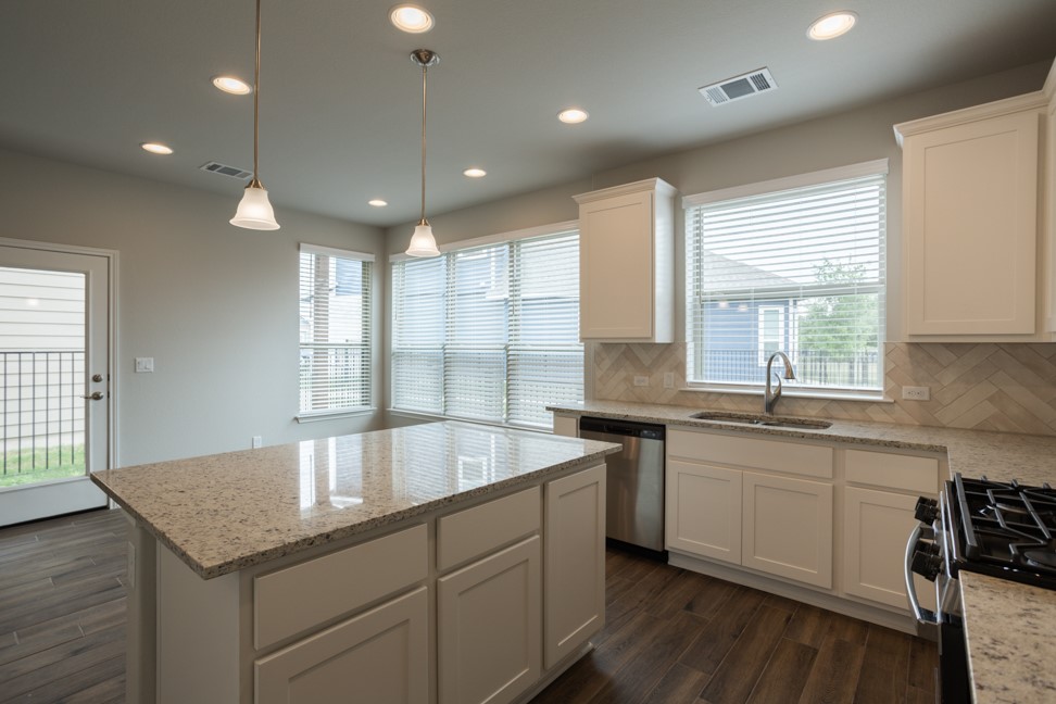 1600 Harwell Loop Kyle, TX 78640 - Photo 10 of 30 a kitchen with center island a sink dishwasher a stove and a refrigerator with wooden floor