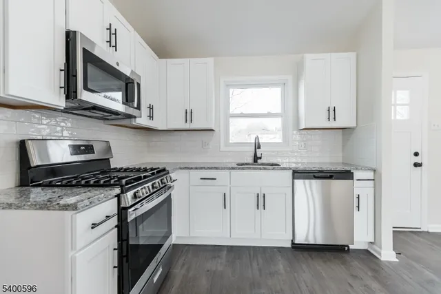 a kitchen with stainless steel appliances granite countertop a sink a stove a microwave and wooden cabinets