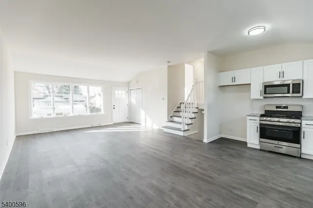 a view of an empty room with a window and kitchen view