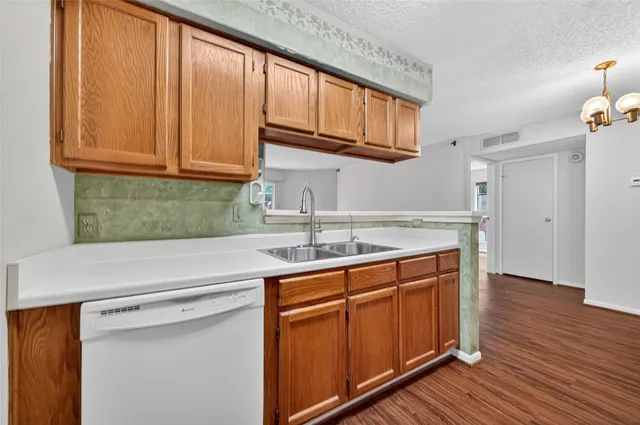 a kitchen with stainless steel appliances granite countertop wooden cabinets a sink and dishwasher with wooden floor
