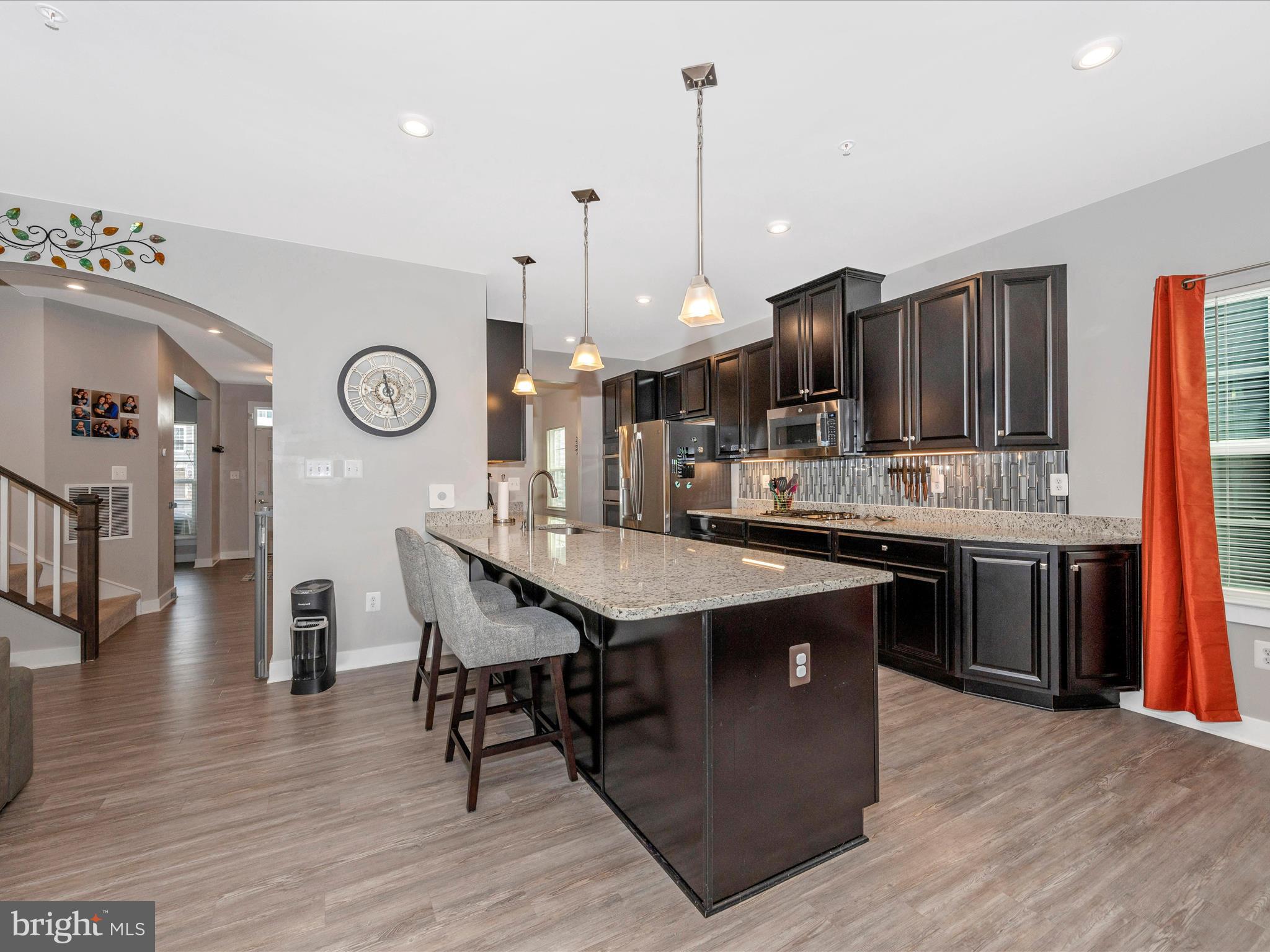 6649 Ballenger Run Boulevard Frederick, MD 21703 - Photo 8 of 42 a kitchen with stainless steel appliances granite countertop a stove a sink dishwasher and a dining table with wooden floor