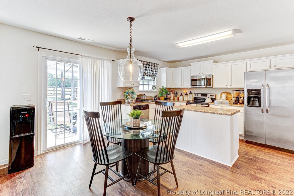 448 Botanical Court Bunnlevel, NC 28323 - Photo 11 of 37 a kitchen with stainless steel appliances granite countertop a stove a refrigerator a dining table and chairs with wooden floor
