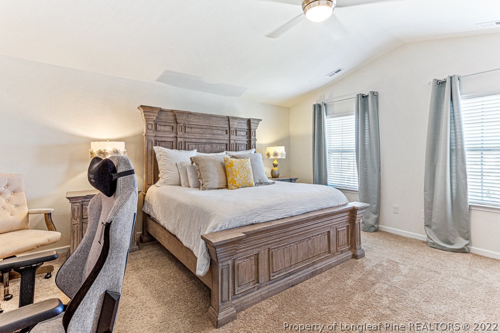 448 Botanical Court Bunnlevel, NC 28323 - Photo 19 of 37 a spacious bedroom with a bed a chandelier and windows