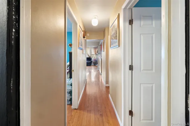 a view of a hallway with wooden floor and a bathroom