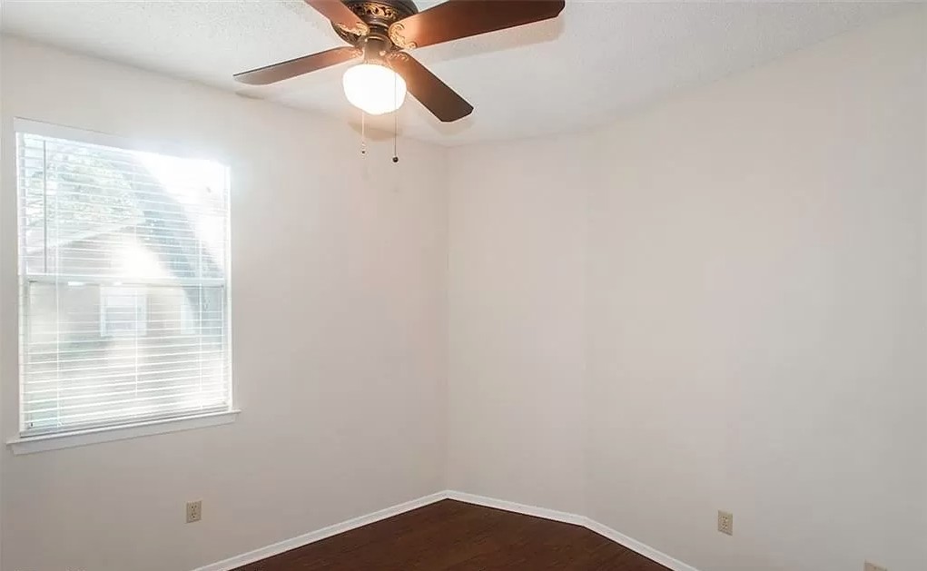 6501 Brush Country Road, Unit 102 Austin, TX 78749 - Photo 10 of 12 Rich wood flooring anchors this versatile bedroom space filled with natural light.