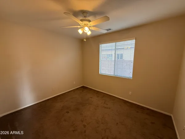 an empty room with a chandelier fan and windows