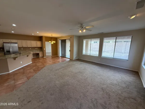 a view of an empty room with a kitchen and a window
