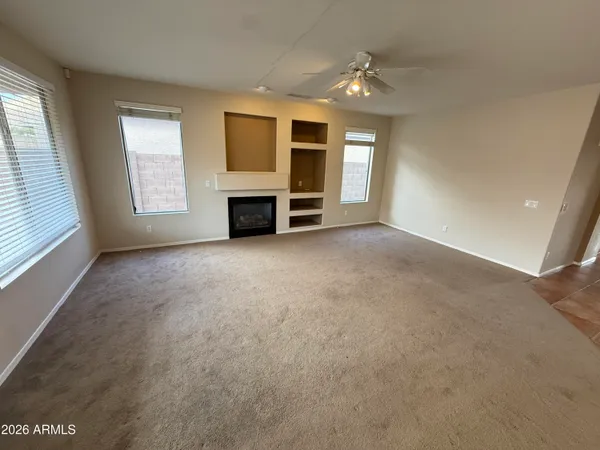 an empty room with windows cabinet and fireplace