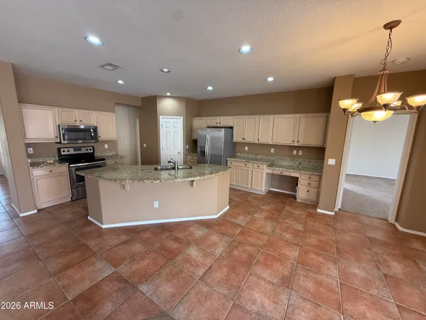 a large kitchen with kitchen island a large counter top stainless steel appliances and cabinets