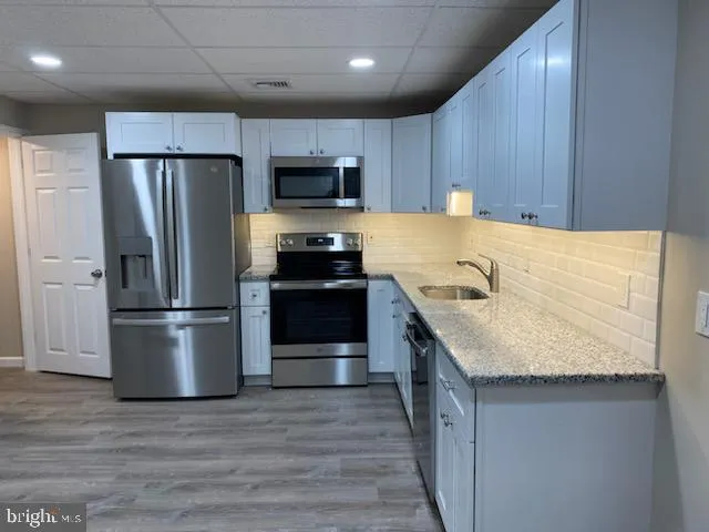 a kitchen with stainless steel appliances granite countertop a refrigerator a stove a sink and a microwave