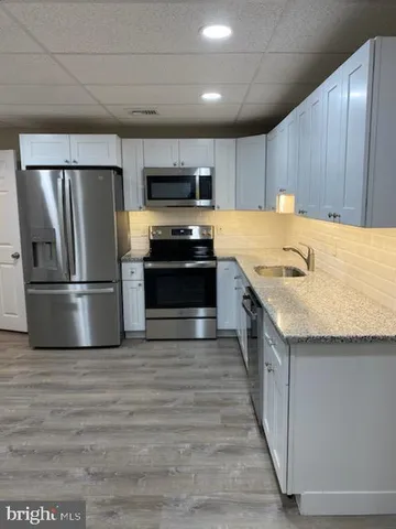 a kitchen with stainless steel appliances granite countertop a refrigerator a stove a sink and a microwave