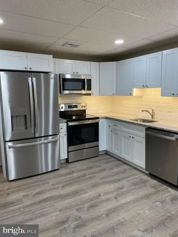 a kitchen with stainless steel appliances granite countertop a refrigerator a stove a sink and a microwave