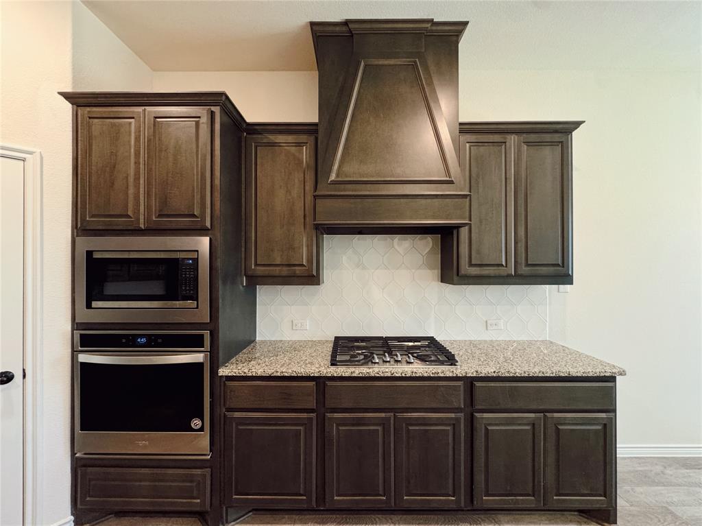 1076 Sublime Drive Forney, TX 75126 - Photo 18 of 40 a kitchen with stainless steel appliances granite countertop a stove and a microwave