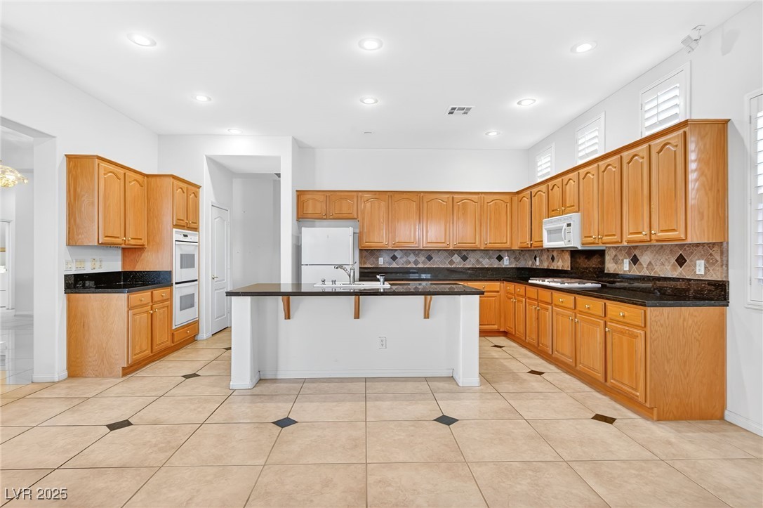 1028 Triumphant Street Henderson, NV 89052 - Photo 14 of 51 Kitchen featuring a breakfast bar, decorative backsplash, light tile patterned floors, and recessed lighting