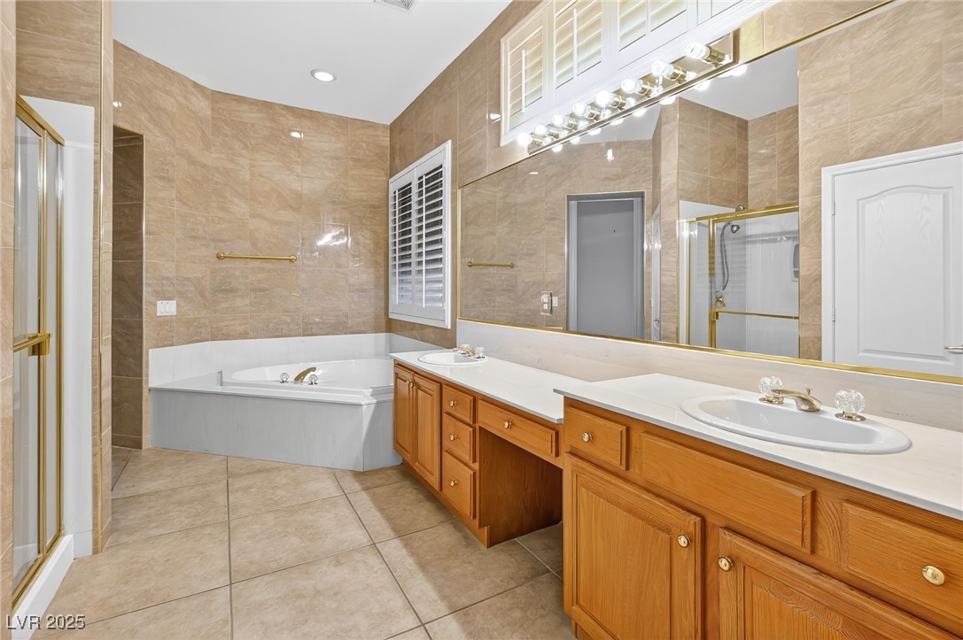 1028 Triumphant Street Henderson, NV 89052 - Photo 23 of 51 Bathroom featuring double vanity, a shower stall, tile walls, a bath, and light tile patterned flooring