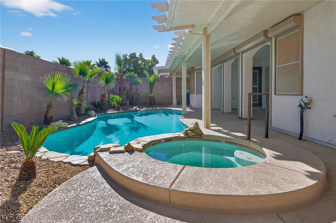 1028 Triumphant Street Henderson, NV 89052 - Photo 41 of 51 View of pool featuring a fenced backyard, a patio, a pool with connected hot tub, and an AC wall unit