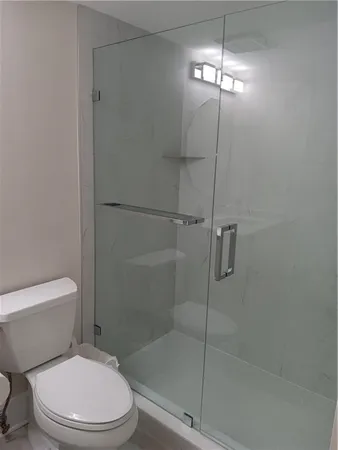 a white toilet sitting next to a shower