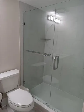 a white toilet sitting next to a shower