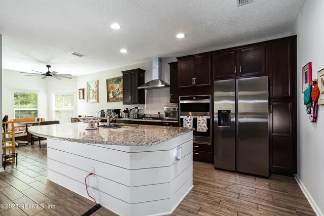 a large kitchen with stainless steel appliances granite countertop a stove a refrigerator and a sink