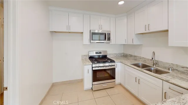 a kitchen with granite countertop white cabinets and stainless steel appliances