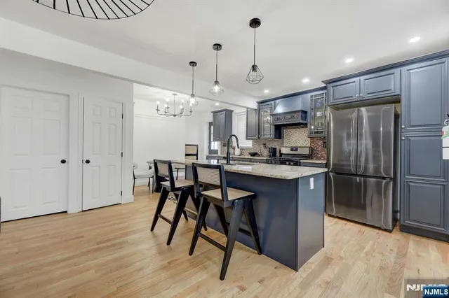 a kitchen with stainless steel appliances a refrigerator a sink dishwasher a stove and white cabinets with wooden floor