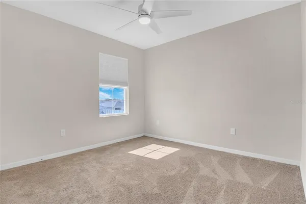 an empty room with a window and a fan