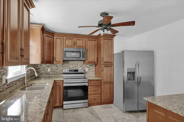 a kitchen with stainless steel appliances granite countertop a sink a stove and refrigerator